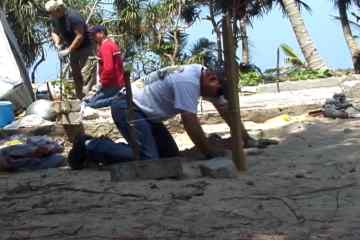 Bruce digs a hole with a coconut shell for a shelter foundation